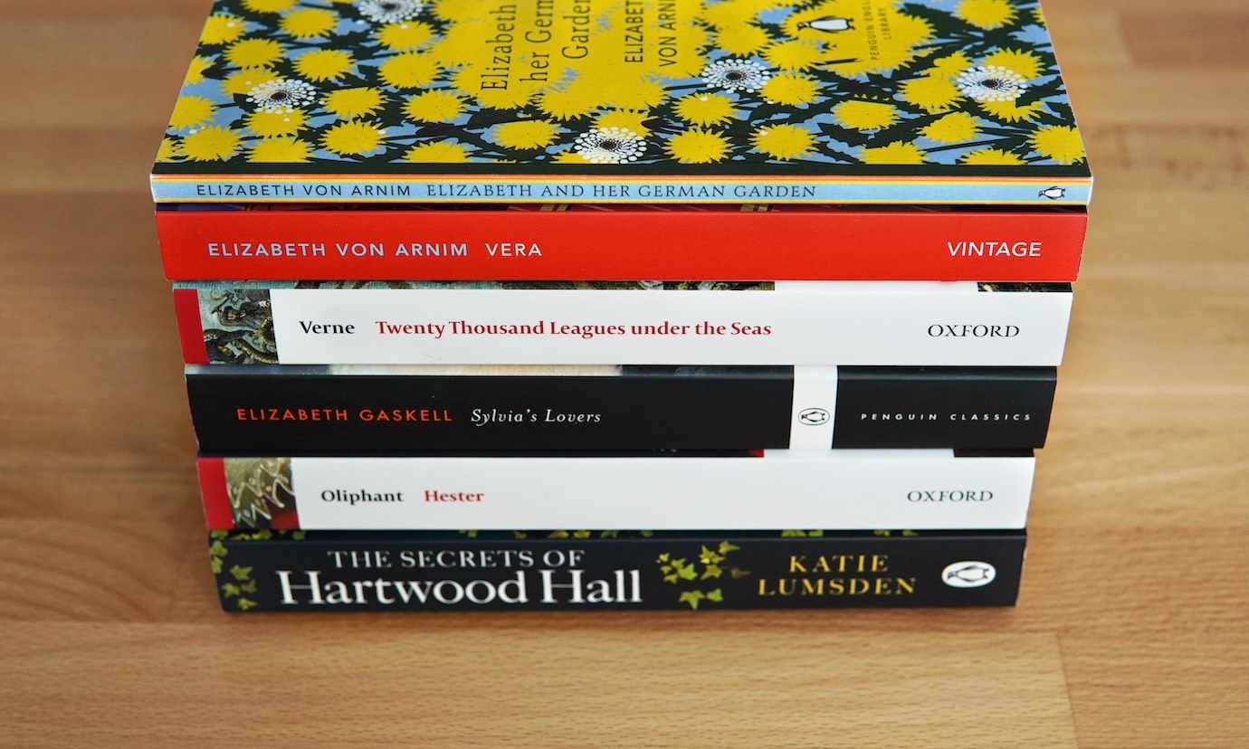 A stack of six softcover books.